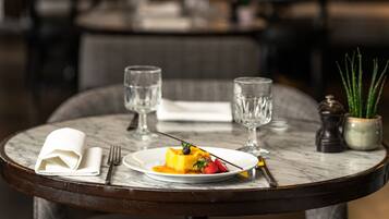 A dining table with a dessert plate, two glasses, a folded napkin, and a salt and pepper shaker.