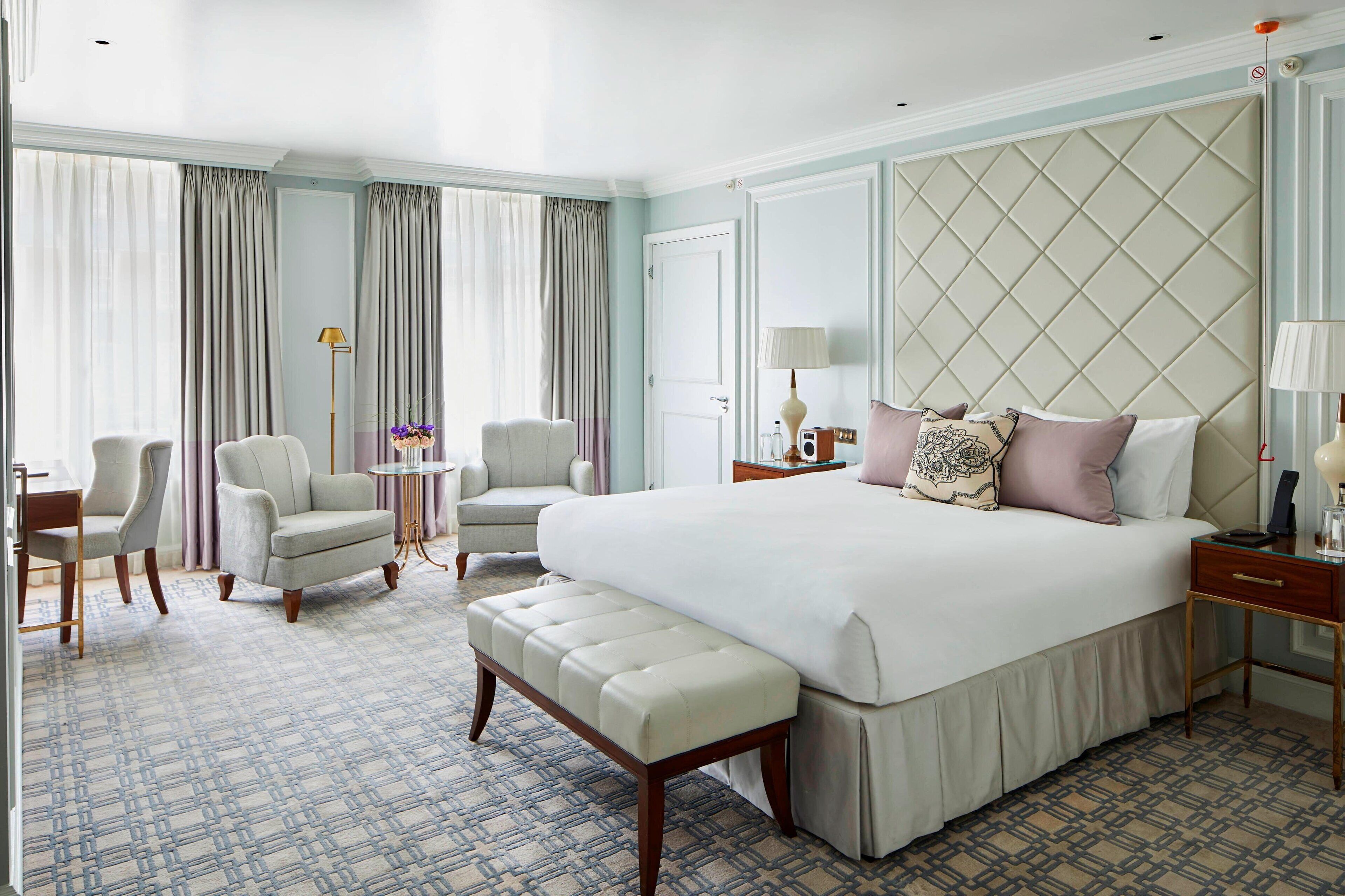 Ruime hotelkamer met een groot bed, twee fauteuils, een tafeltje en een bank.