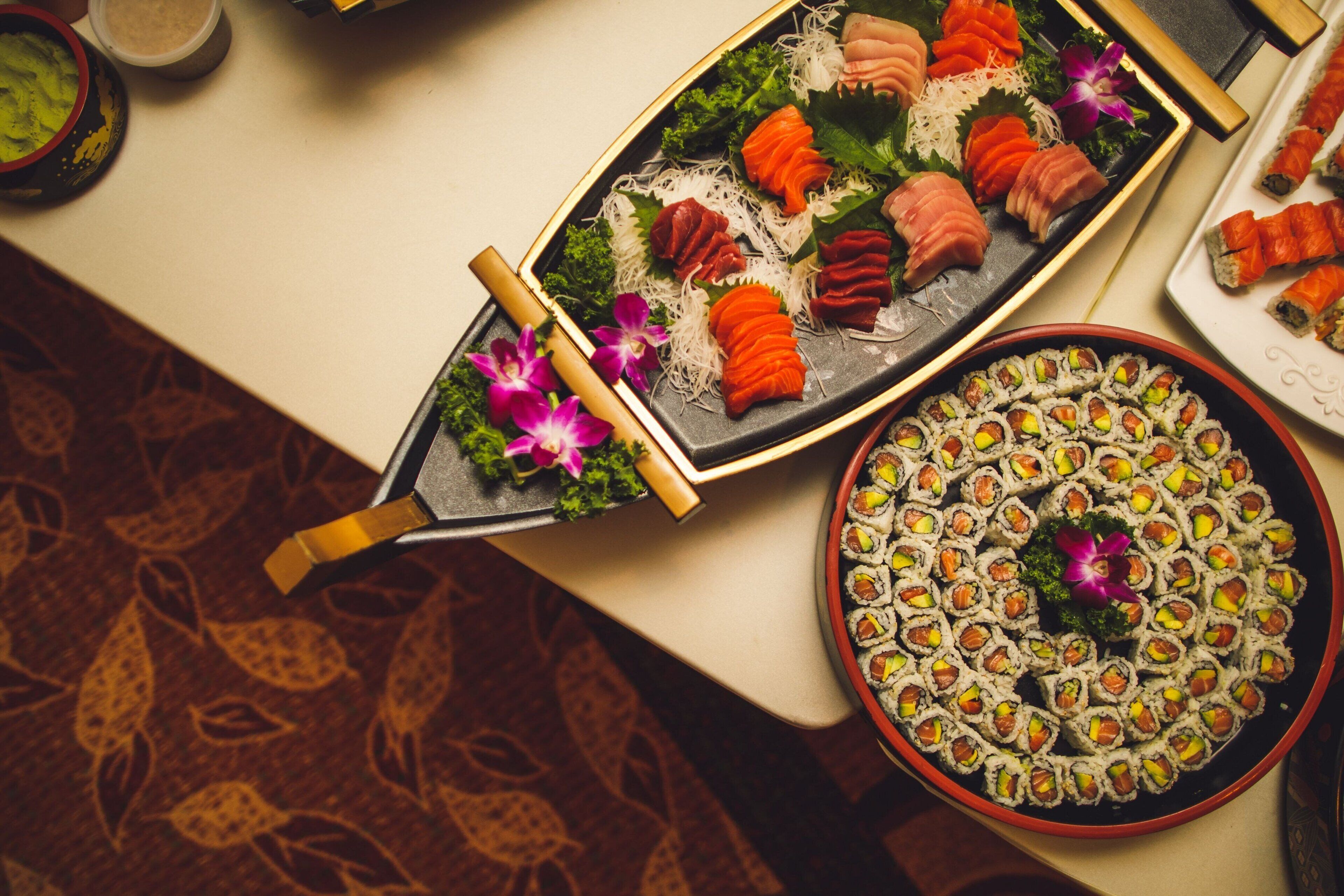 Una bandeja de sushi con distintos tipos de sushi y una flor decorativa.