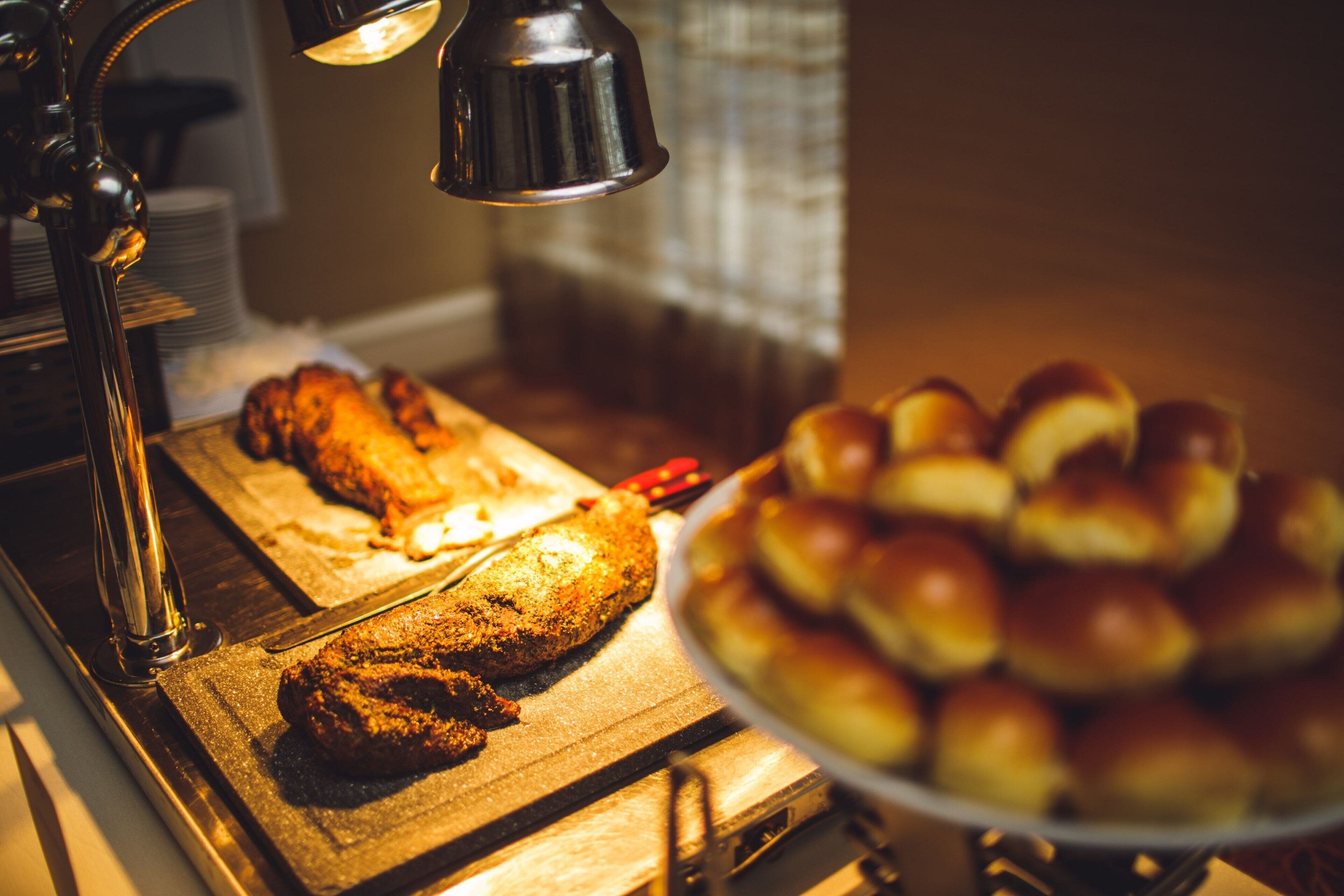 A kitchen counter with a loaf of bread and a plate of rolls.