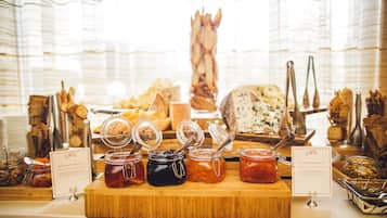 A buffet with various food items and condiments, including jars of preserves and cheese.