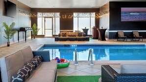 A poolside area with a sofa, lounge chairs, and a pool.