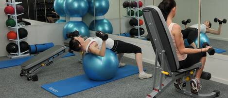 A gym with exercise equipment, including a rowing machine, exercise balls, and dumbbells.