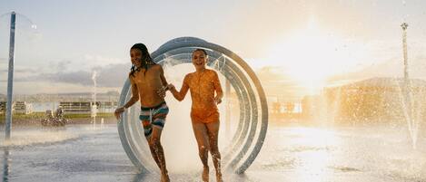 Two people walking through a water feature with a circular structure.