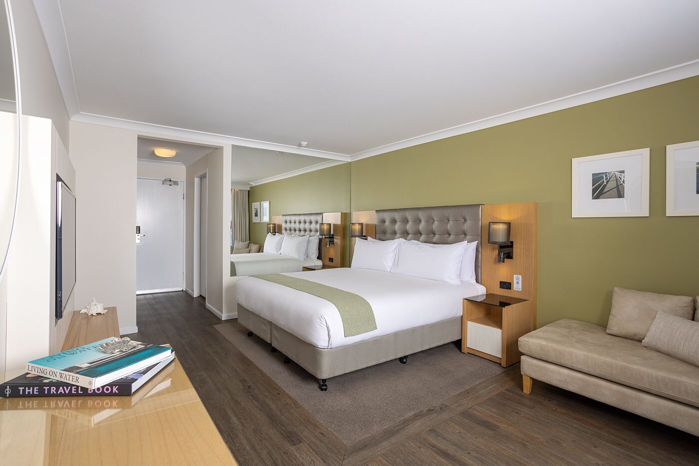 Una habitación de hotel con una cama grande, una mesita de noche, un sofá y una estantería.