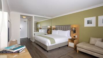 Una habitación de hotel con una cama grande, una mesita de noche, un sofá y una estantería.