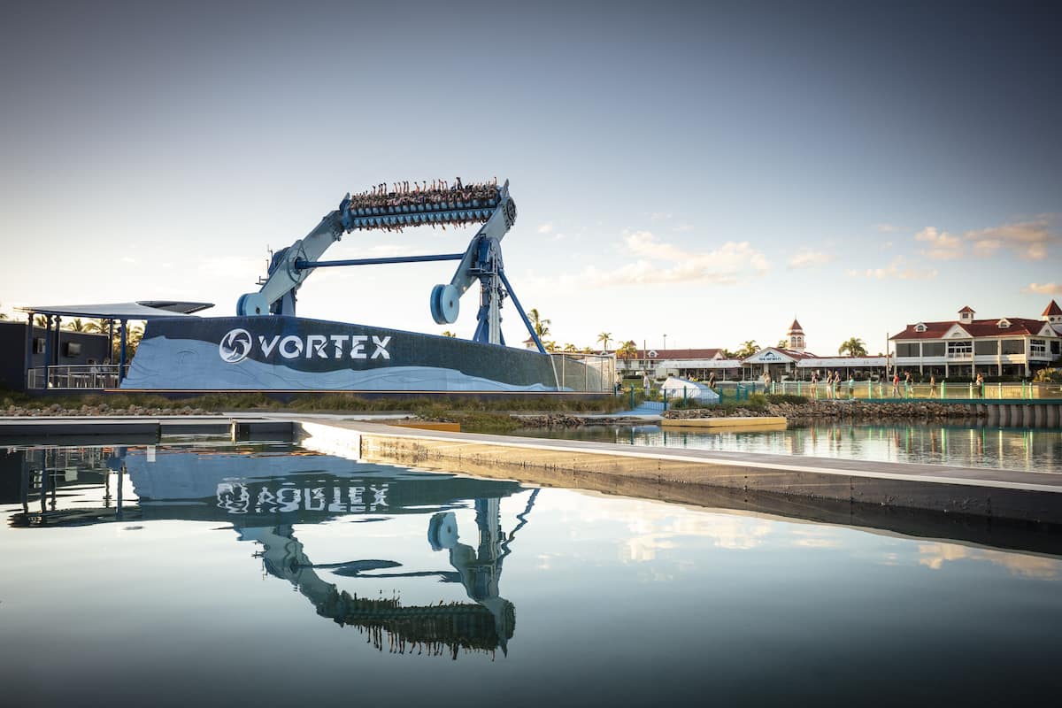 A water ride with a large structure labeled "VORTEX" reflecting on the water surface.