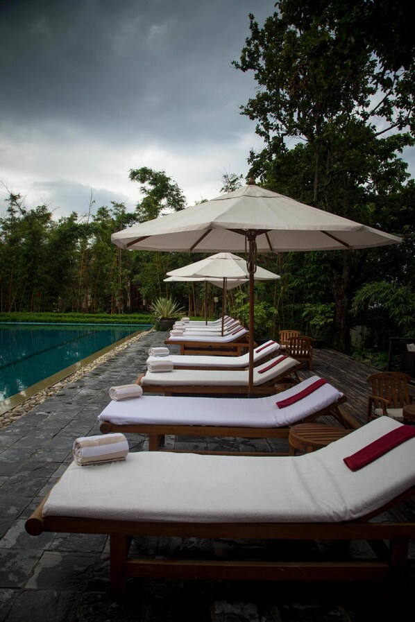 Una piscina al aire libre, sombrillas, tumbonas