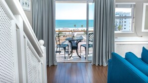 A balcony with a view of the ocean, a table with chairs, and a blue sofa. - The Bantry Bay Aparthotel by Totalstay (Cape Town)