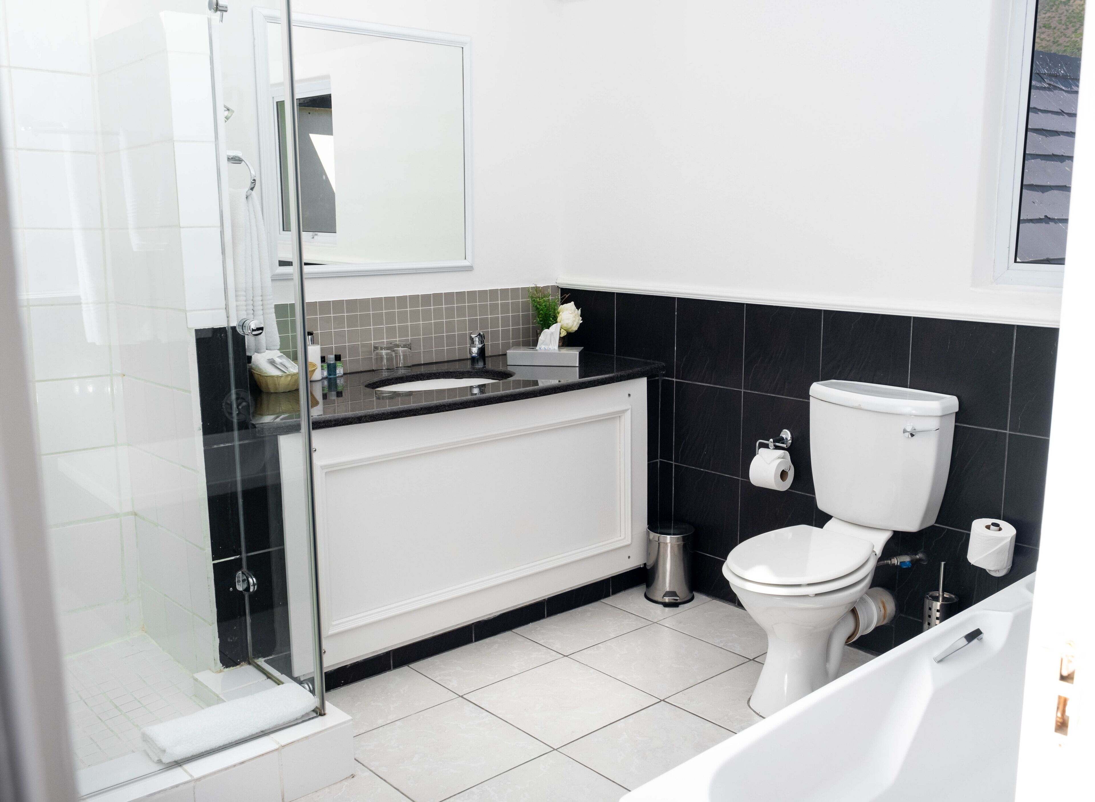 Ein modernes Badezimmer mit Duschkabine aus Glas, Toilette in Weiß und einer Badewanne.