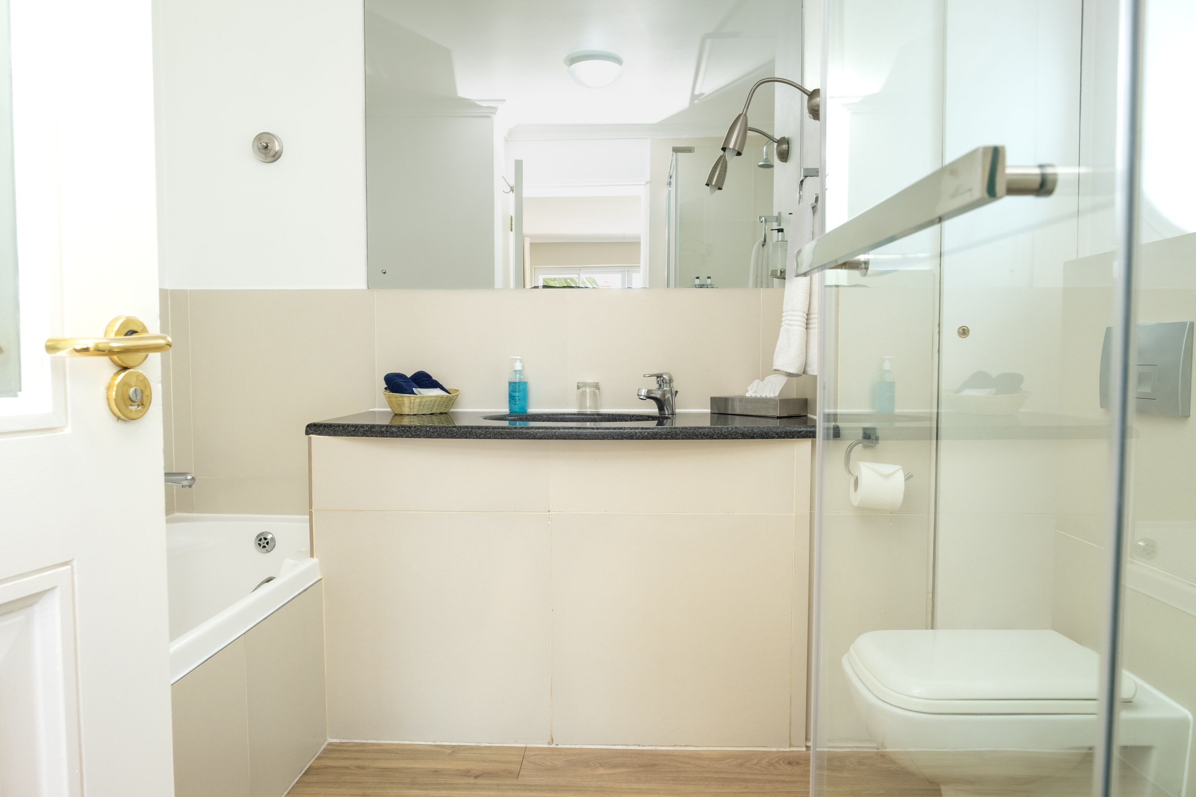 Un baño moderno con cabina de ducha de vidrio, una bañera blanca y un lavabo con artículos de aseo.