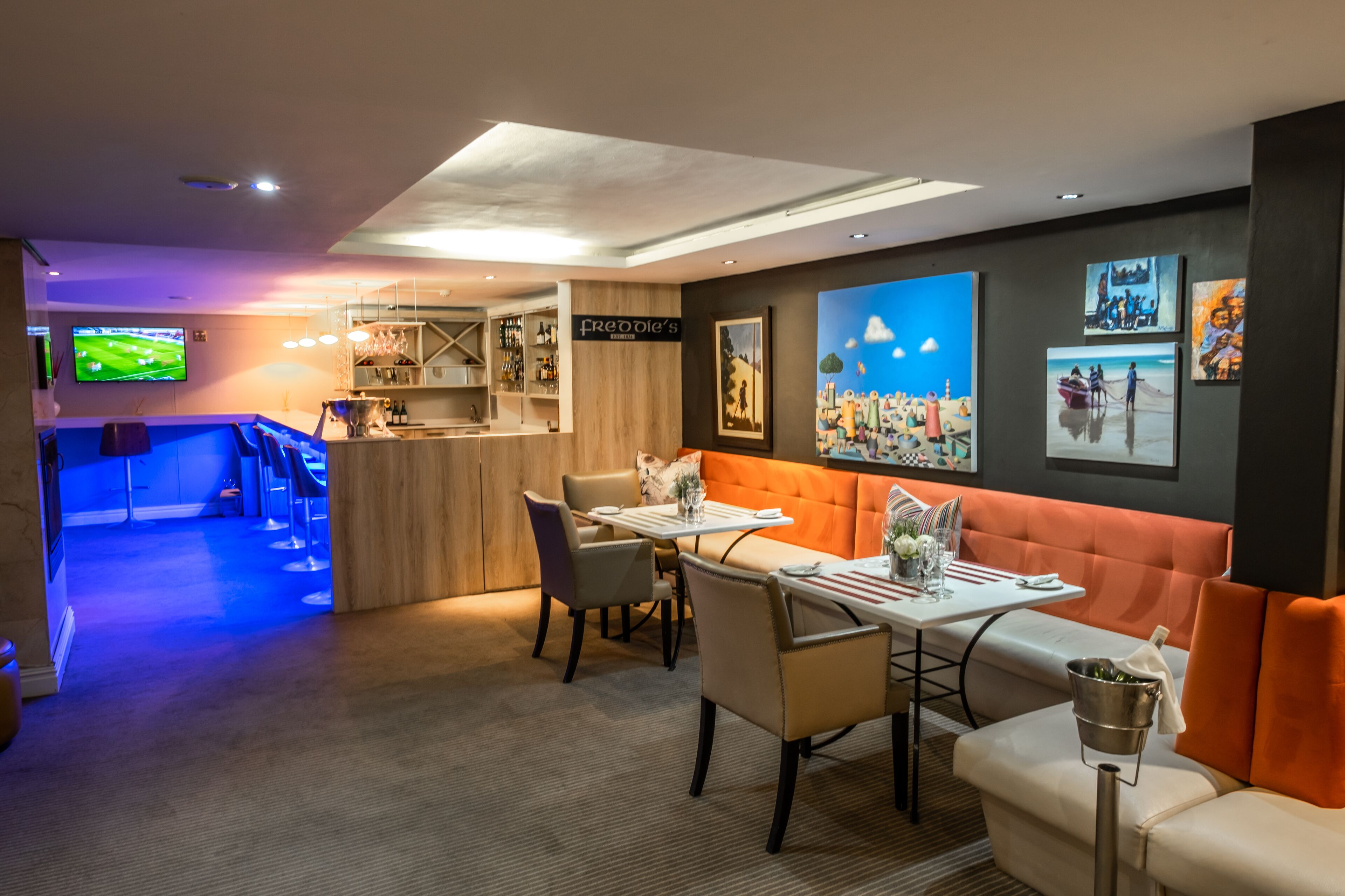 A modern hotel lobby with a bar area, seating arrangements, and artwork on the walls.
