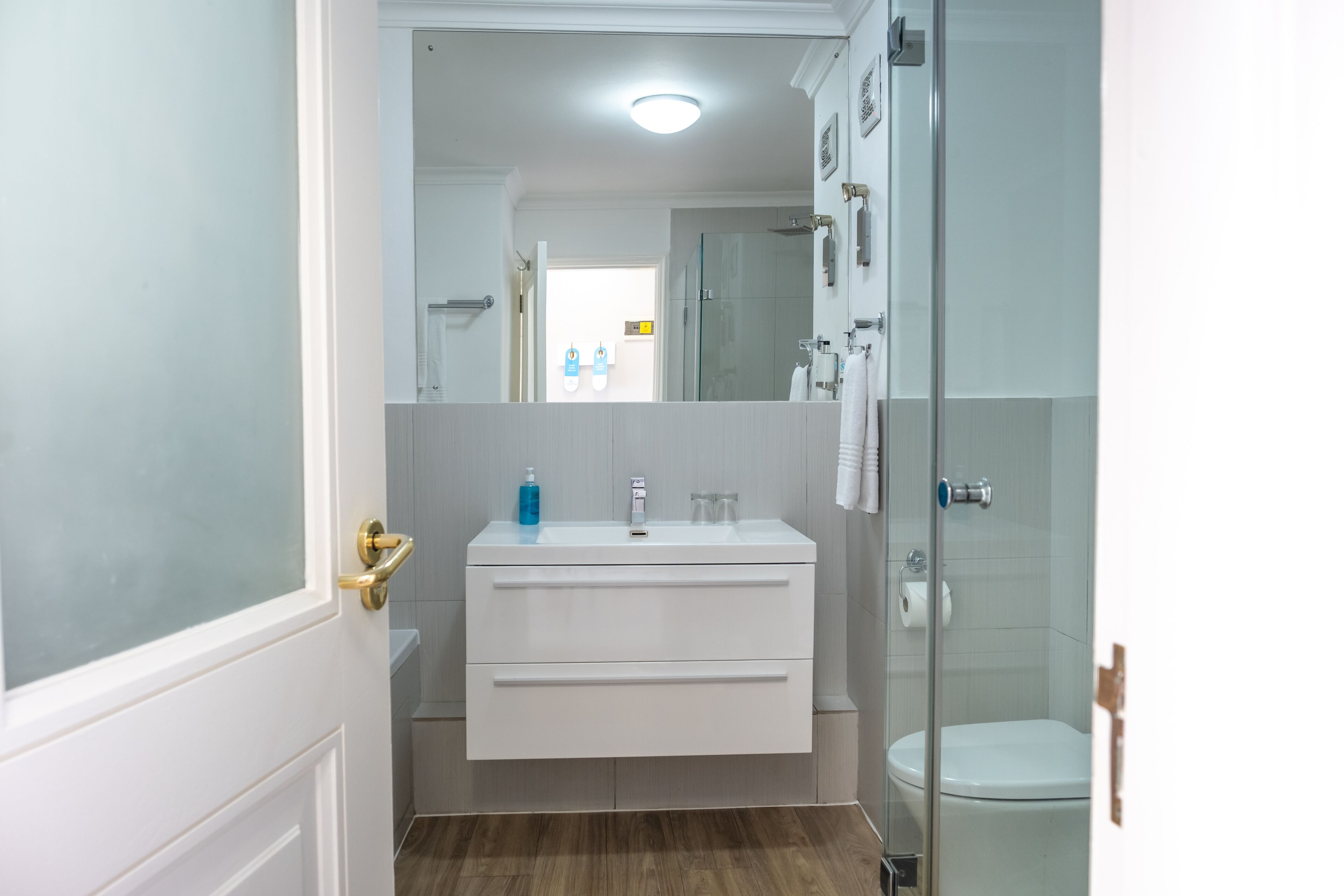 A bathroom with a white vanity, a glass shower enclosure, and a toilet.