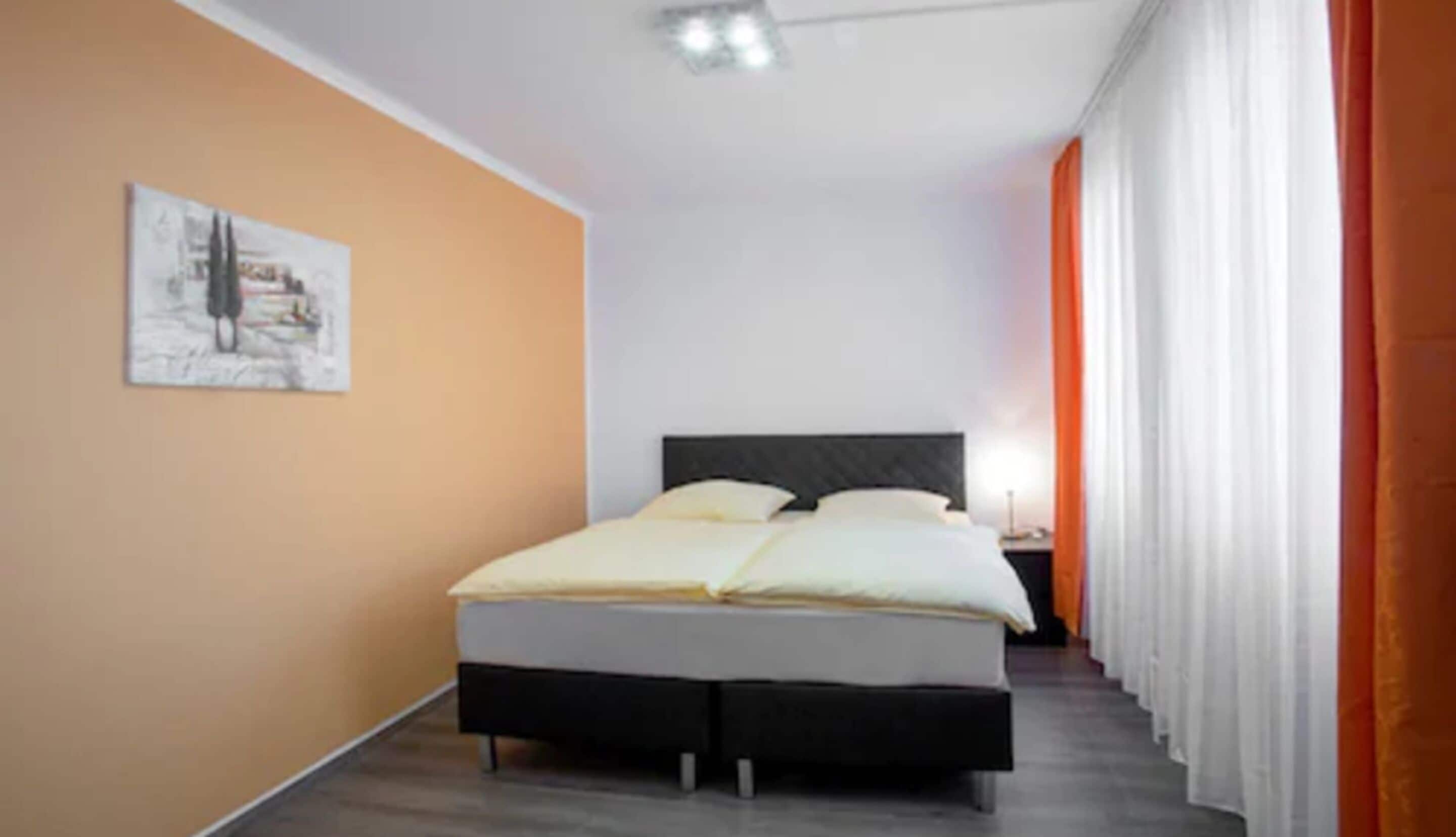 A bedroom with a bed, a nightstand, a lamp, and a painting on the wall.