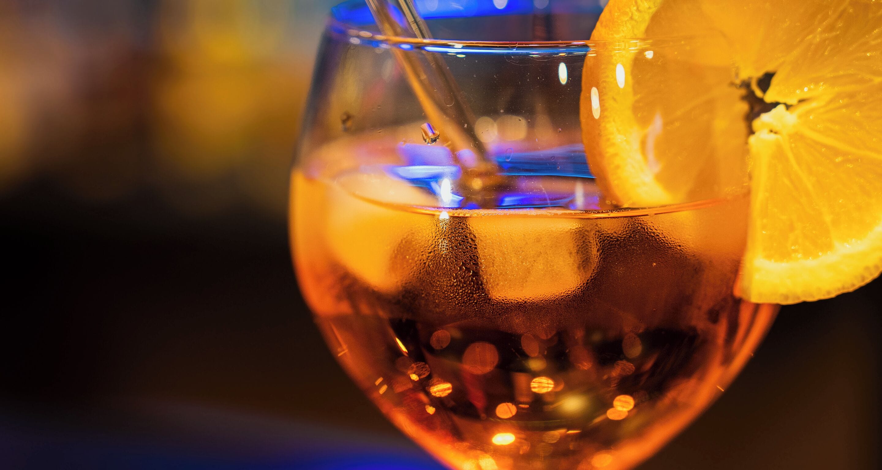 A close-up of a glass with a lemon slice and a straw.