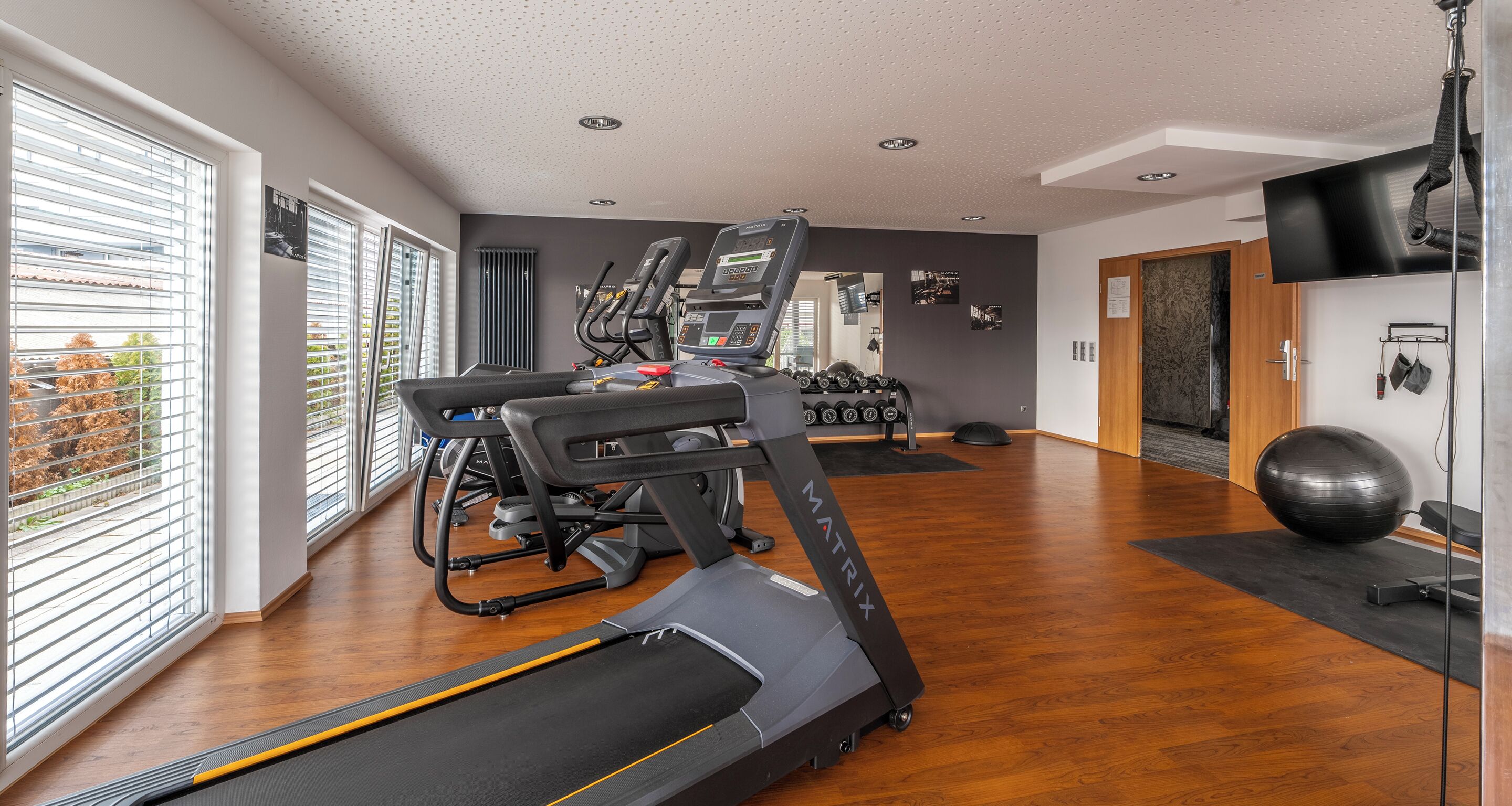 Une salle de sport moderne équipée de tapis de course, de vélos elliptiques et de poids libres.