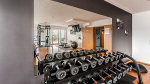 A gym with a wall-mounted dumbbell rack, a large exercise ball, and a wooden door. - PLAZA INN Heilbronn (Heilbronn)