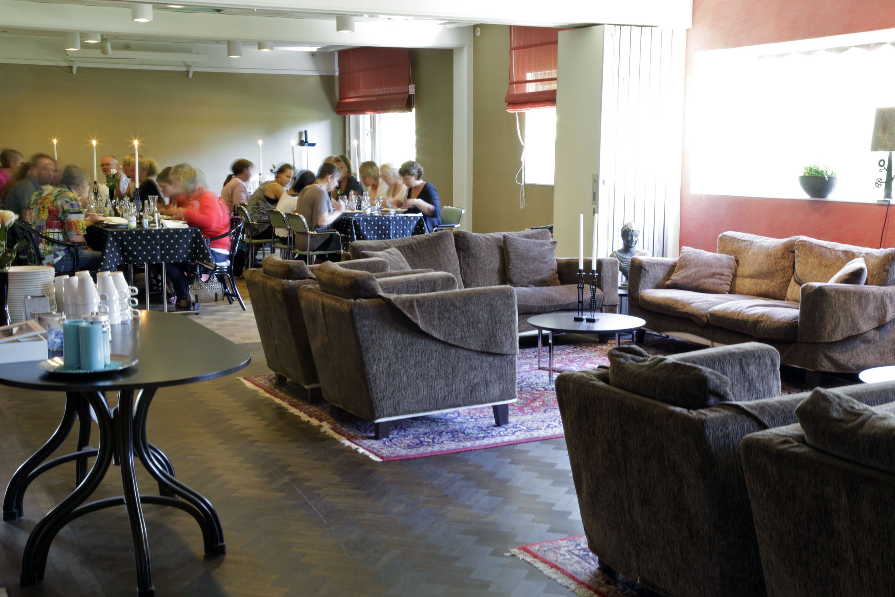 A dining area with a group of people seated at a table, surrounded by sofas and a coffee table.