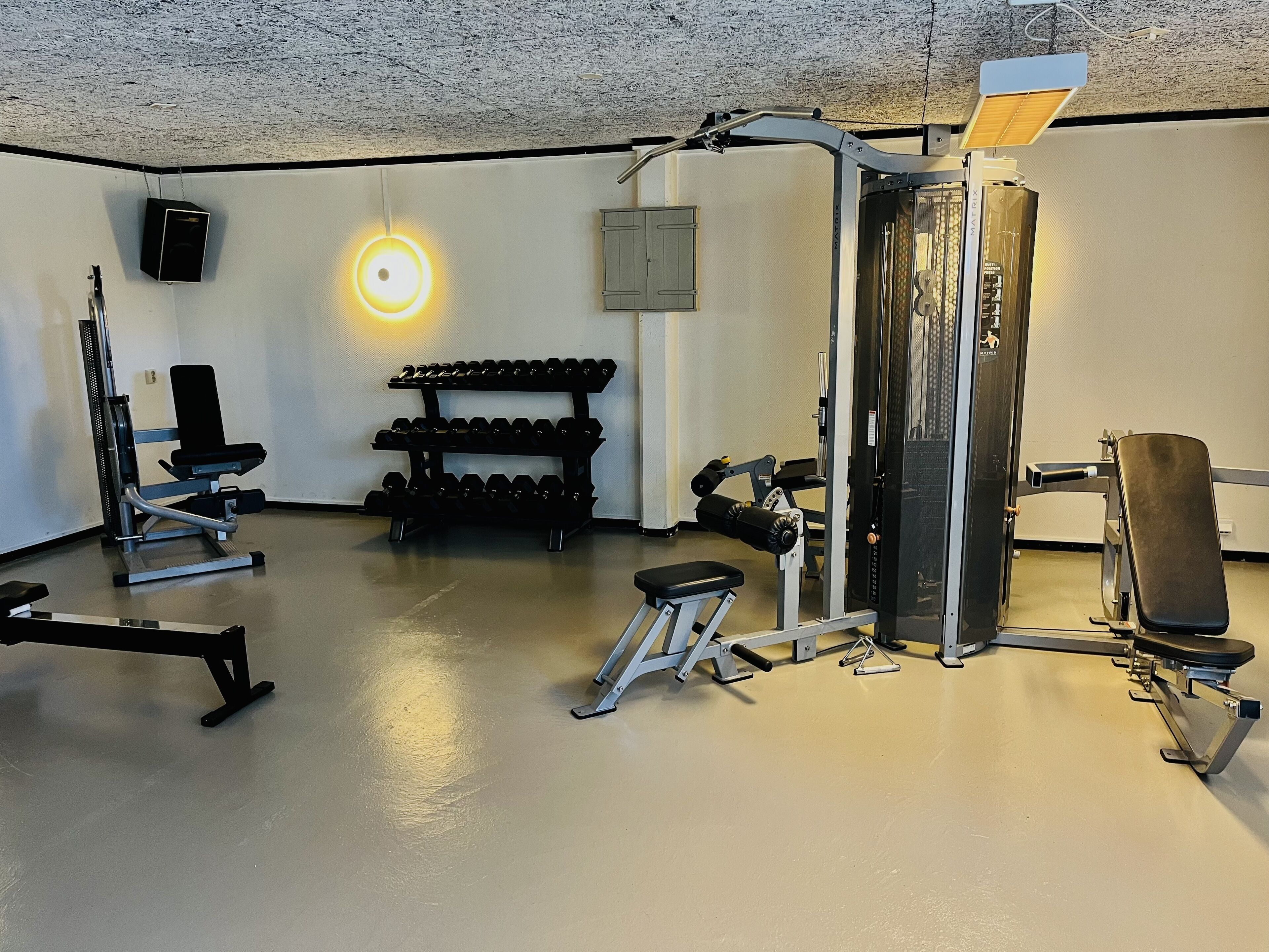 A gym with various exercise equipment, including dumbbells, benches, and weight machines.