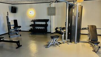 Un gimnasio con diversos equipos de ejercicio, incluyendo pesas, bancos y máquinas de musculación.