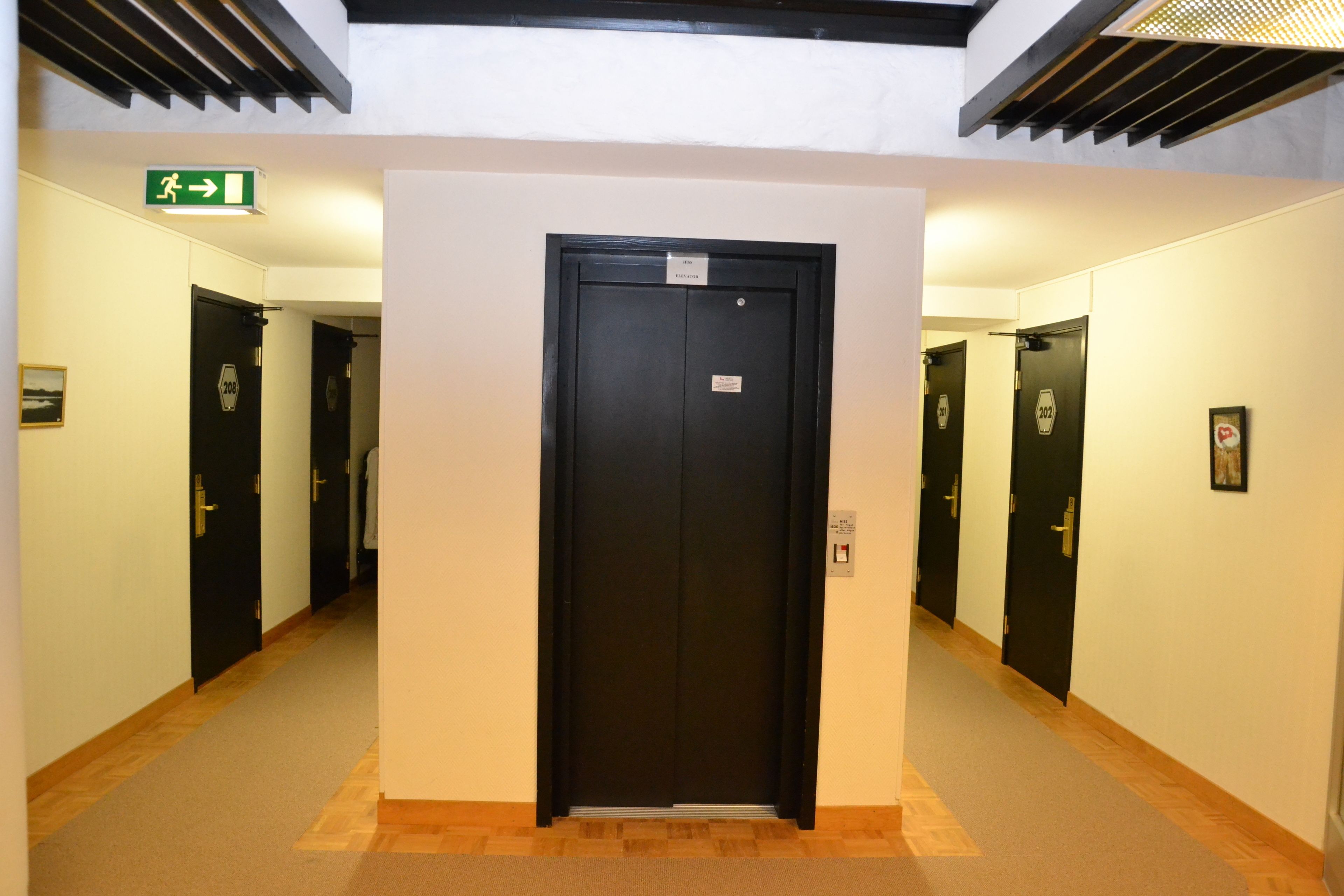 Un pasillo con una puerta negra central, flanqueado por dos puertas negras a cada lado.
