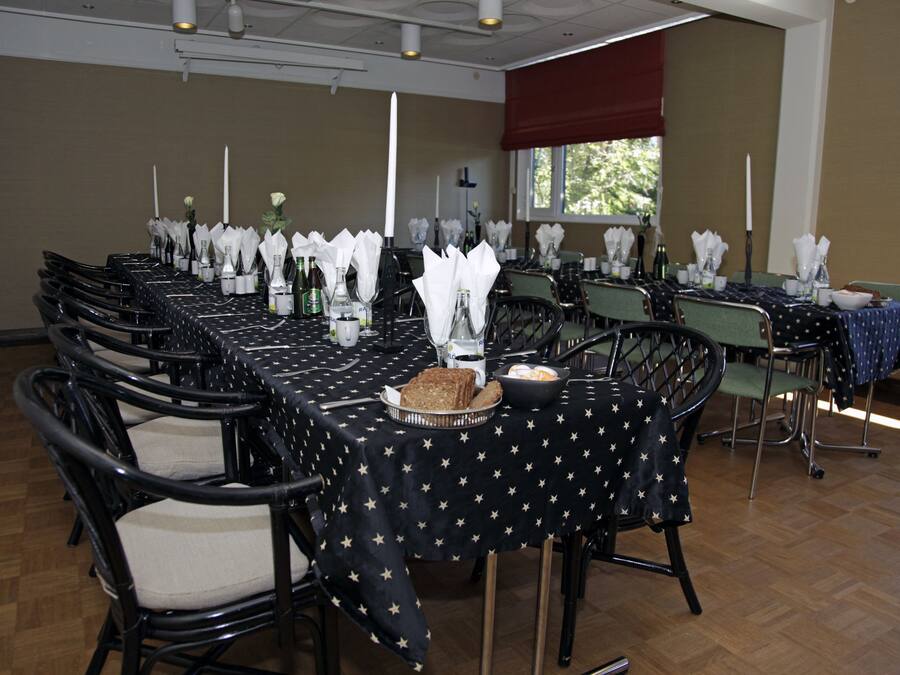Une salle de conférence avec plusieurs tables préparées pour une réunion, chacune étant agrémentée de serviettes blanches, de bouteilles et d'un centre de table.