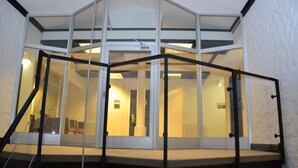 Habitación de hotel moderna con balcón de cristal, una escalera y vista al interior.