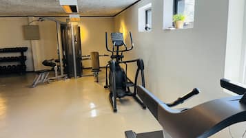 Une salle de sport équipée de matériel d’exercice, d’un banc et d’une fenêtre avec une plante.