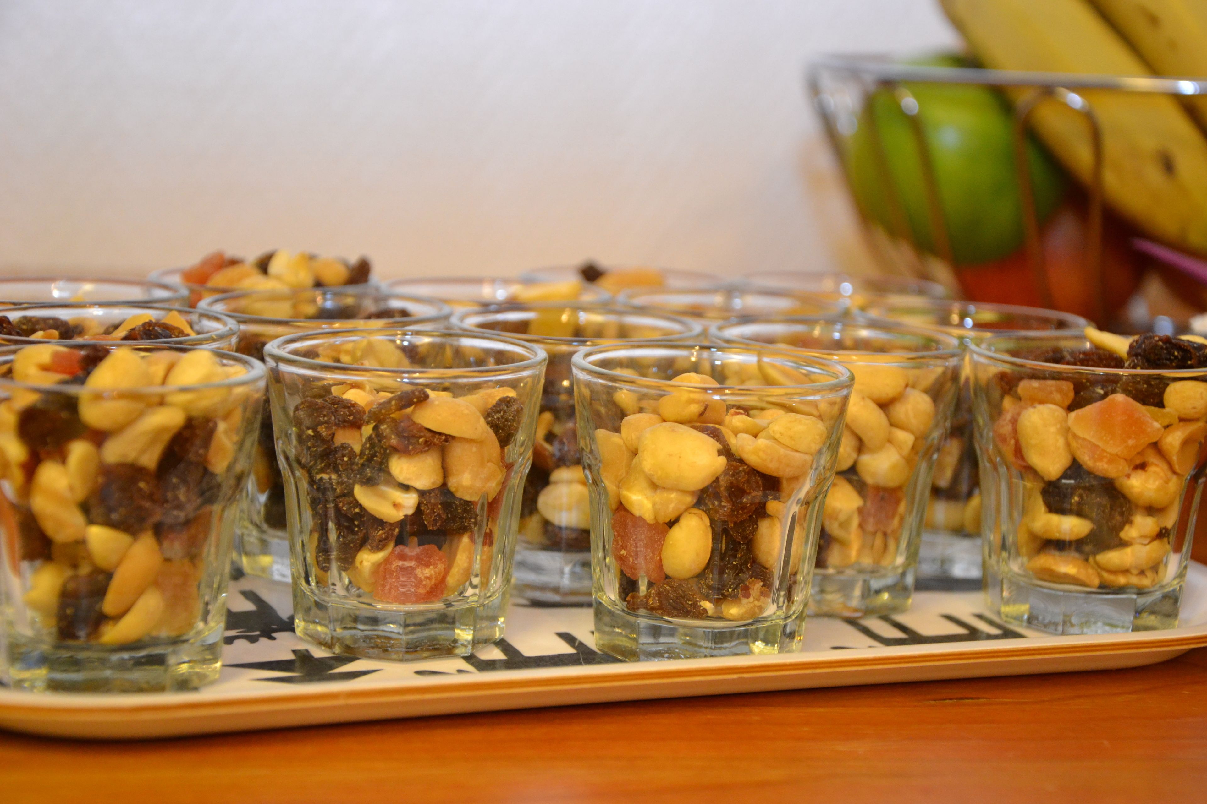 Un plateau rempli de petits verres contenant un mélange de fruits secs et de noix.