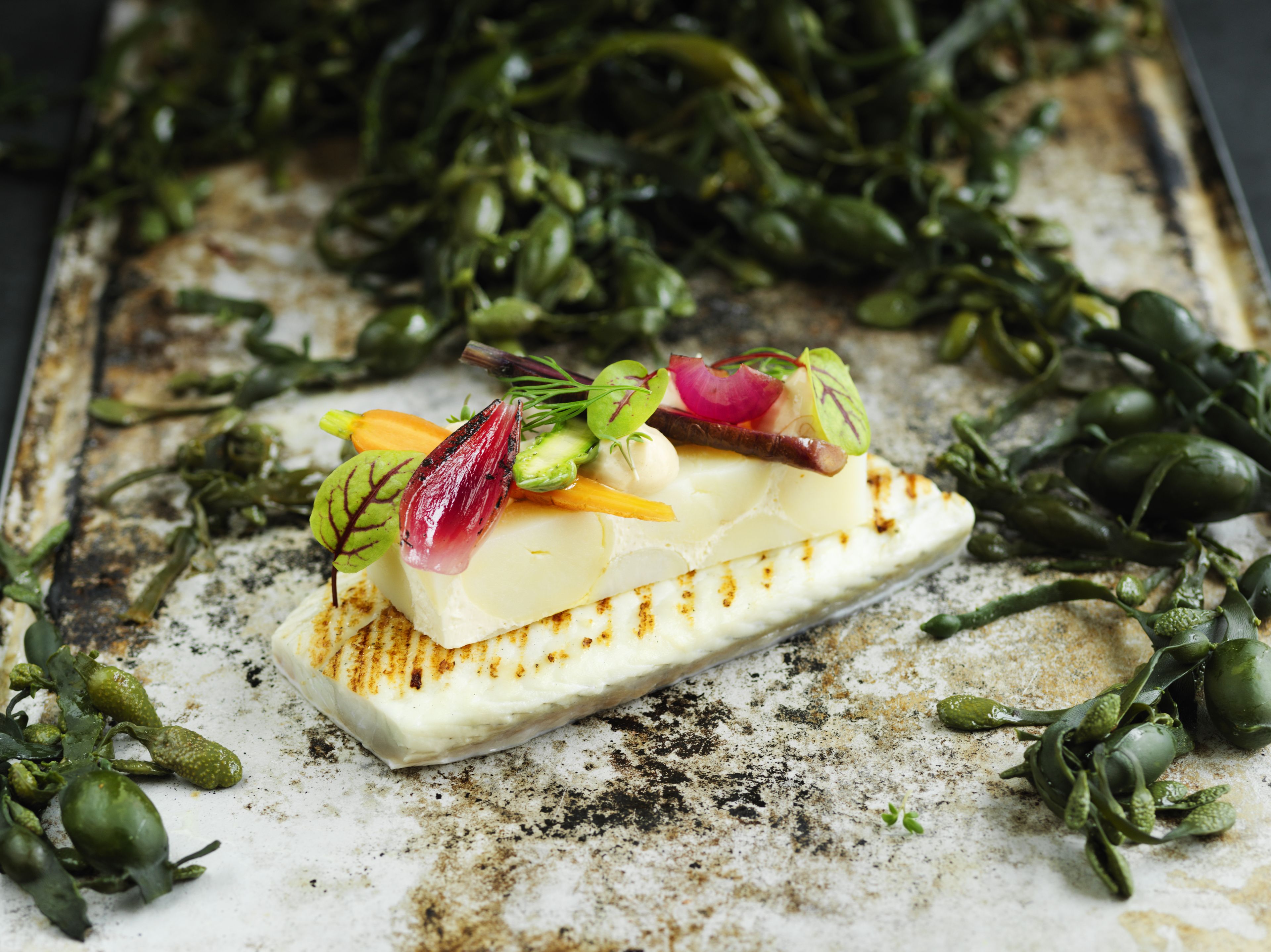 A dish with a white base, possibly cheese, topped with various vegetables and garnishes.