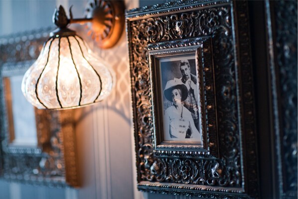 Un marco ornamentado con una fotografía blanco y negro, un aplique decorativo y un papel tapiz estampado.