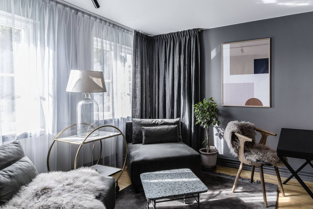 Una sala de estar moderna con un sofá, una mesita, una lámpara y una silla.