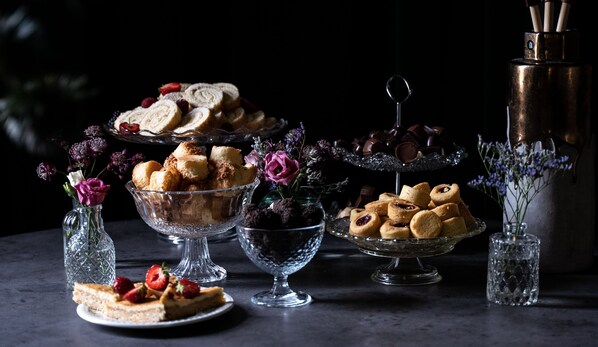 A table with various desserts and flowers.