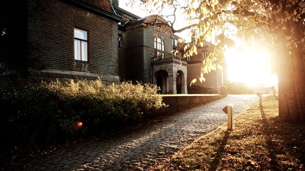 A historic building with a cobblestone pathway leading to a gated entrance. - Bjertorp Slott (Kvanum)