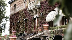 A building with ivy-covered walls, outdoor seating with chairs and tables, and a large decorative lantern. - Bjertorp Slott (Kvanum)