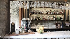 A bar area with shelves of liquor bottles, hanging wine glasses, and a coffee display. - Bjertorp Slott (Kvanum)