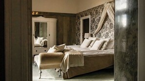 A bedroom with a bed, a chair, a mirror, and a window with curtains. - Bjertorp Slott (Kvanum)