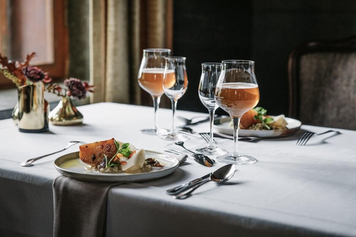 Una mesa de comedor con platos de comida, vasos de bebida y cubiertos.