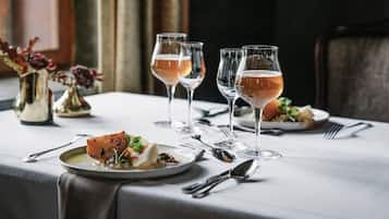 Una mesa de comedor con platos de comida, vasos de bebida y cubiertos.