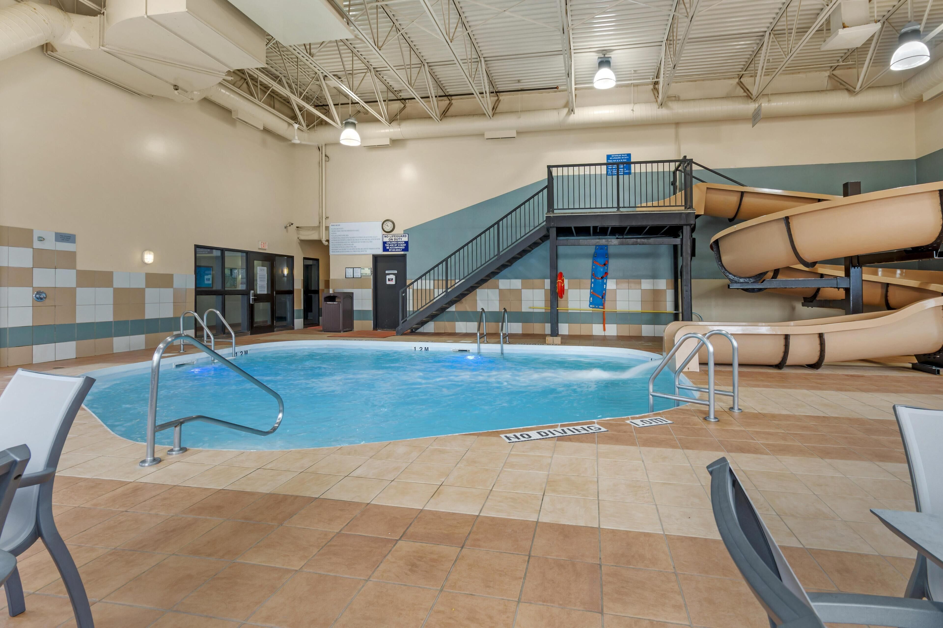 An indoor swimming pool with a slide, a staircase, and a lifeguard station.