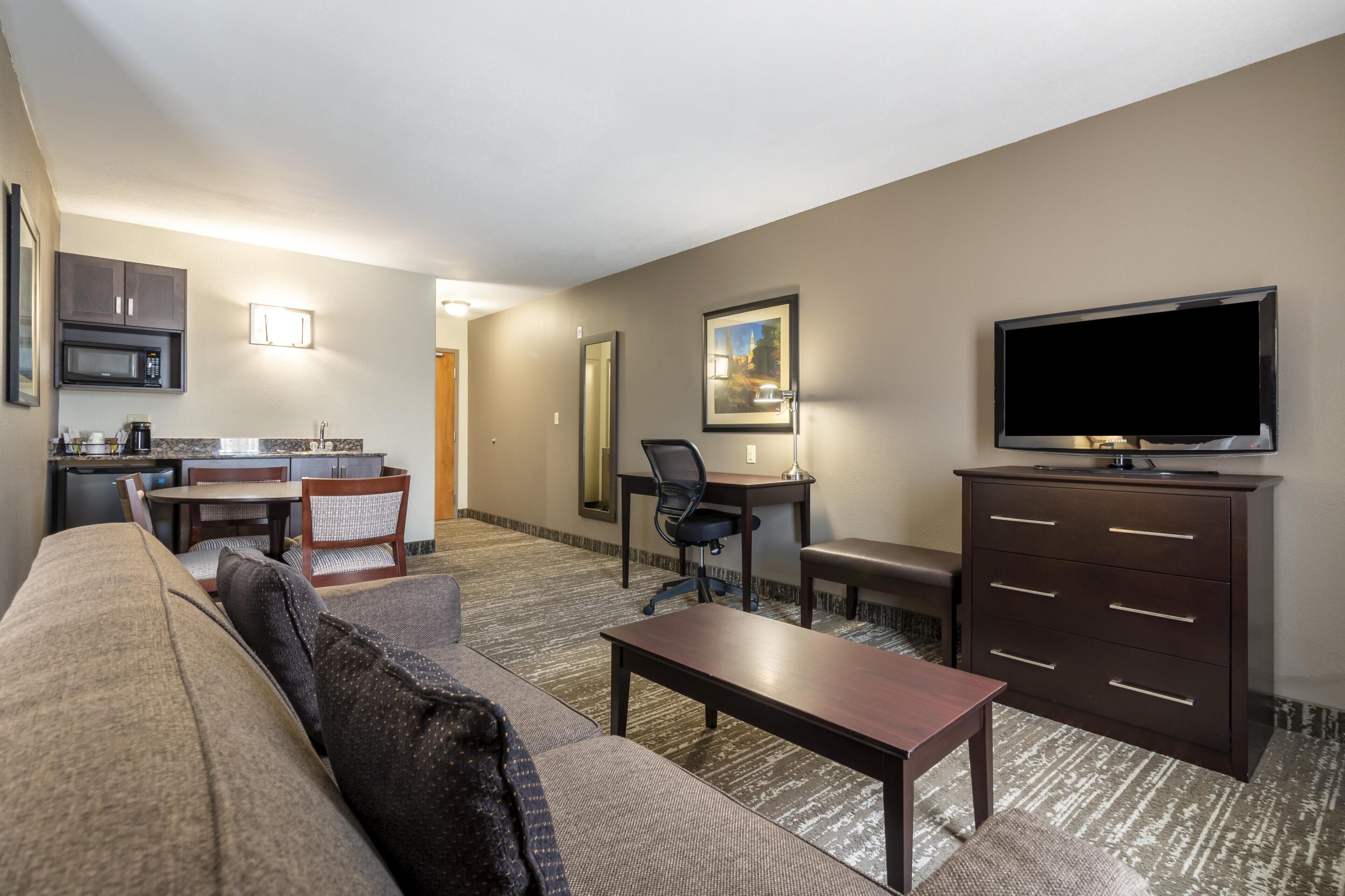 Una habitación de hotel con sala de estar, kitchenette y televisor.