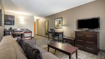 Una habitación de hotel con sala de estar, kitchenette y televisor.
