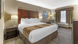 A hotel room with a large bed, two bedside tables with lamps, a desk, a chair, a window with curtains, and a wall-mounted picture. - Best Western Plus Pembina Inn & Suites (Winnipeg)