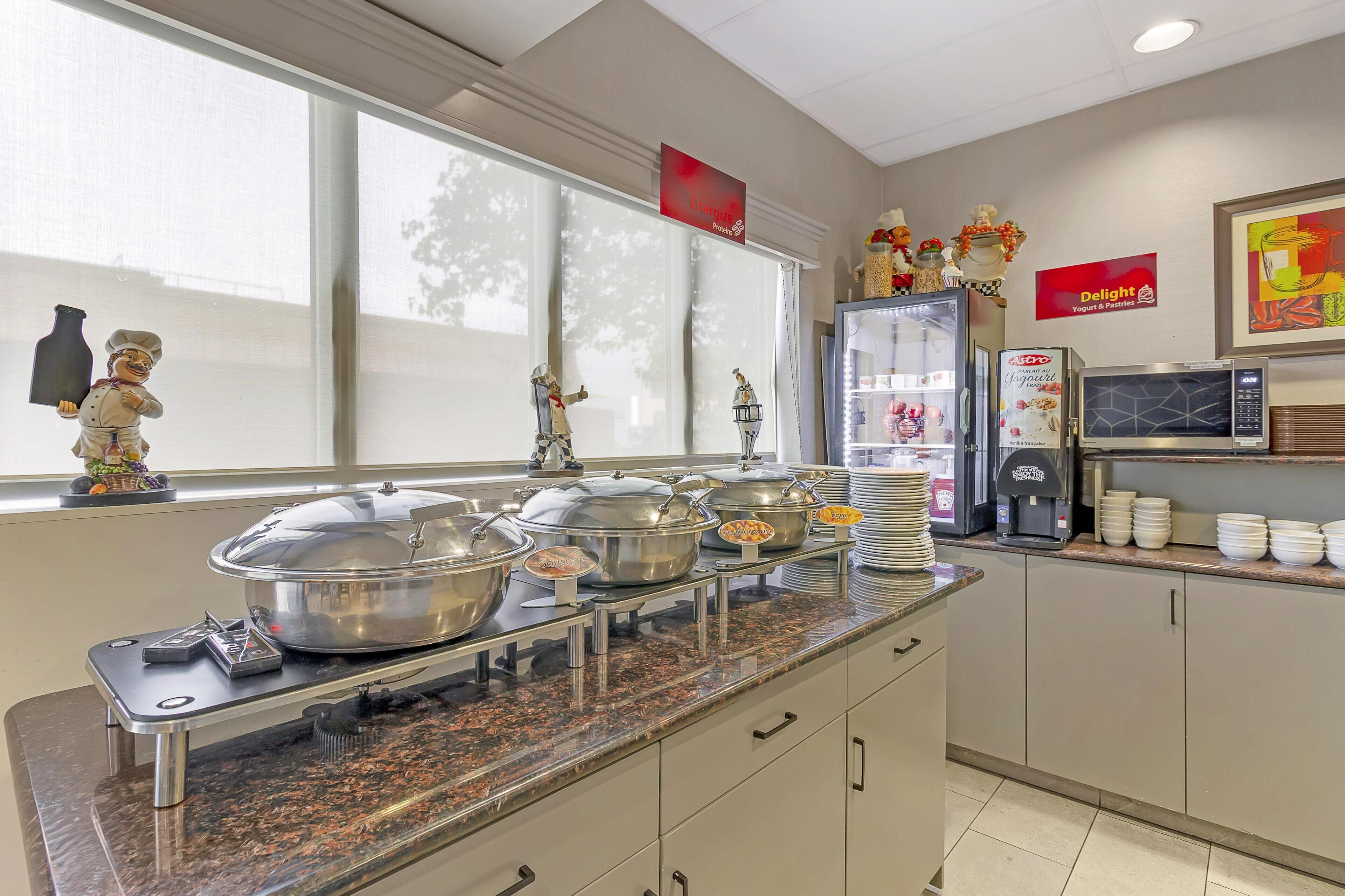 A buffet setup with multiple serving stations, a coffee machine, and a refrigerator.