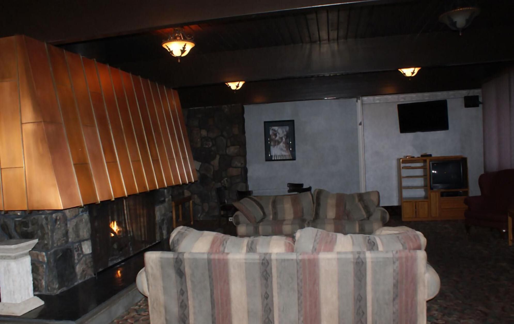 A cozy living room with a fireplace, a stone wall, and a television.