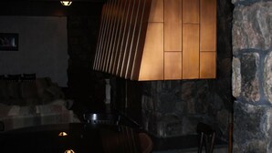 A dimly lit room with a stone wall, a wooden table, and a chair. - Burntwood Hotel (Thompson)