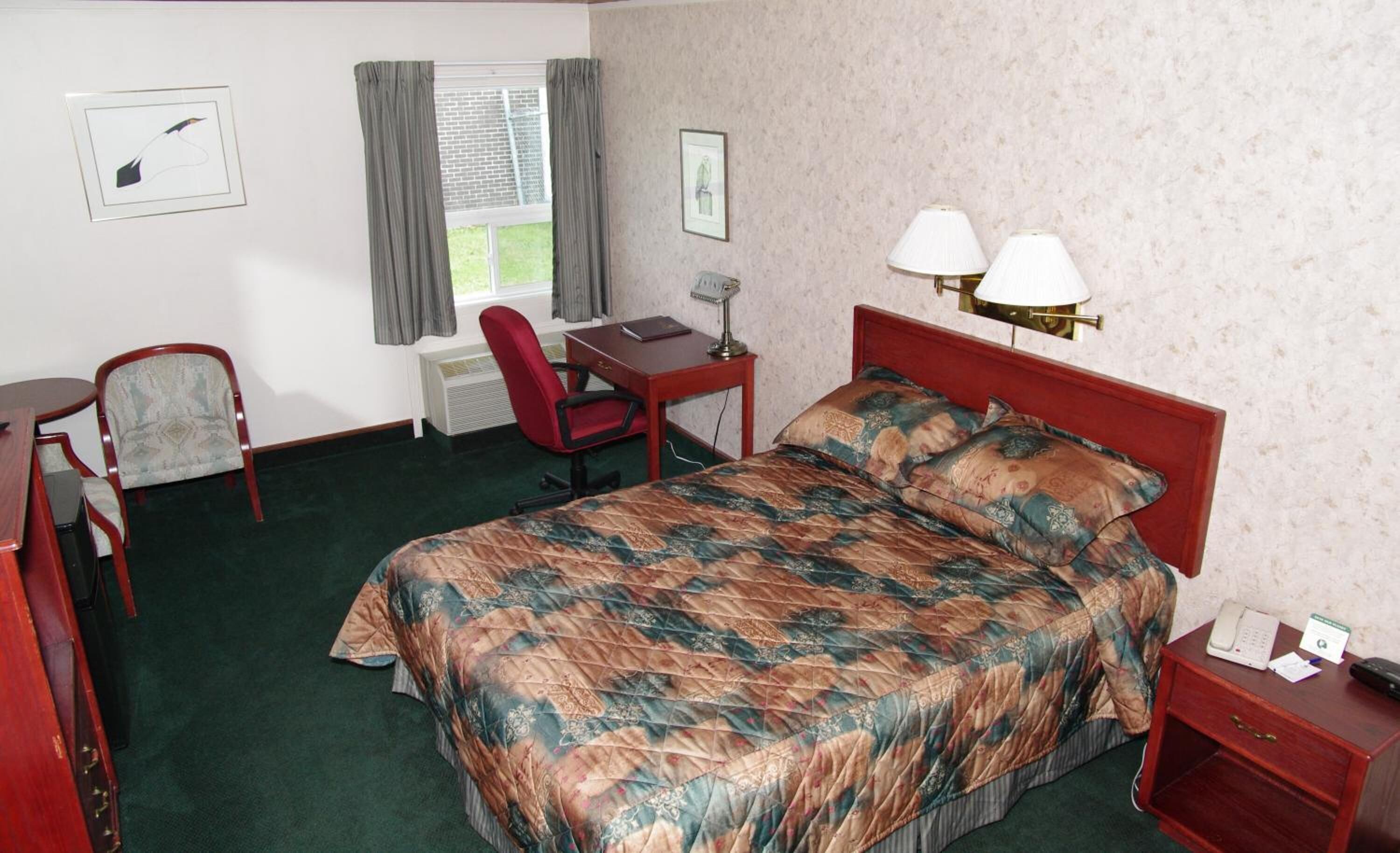 Una habitación de hotel con cama, escritorio, silla y dos lámparas de noche.