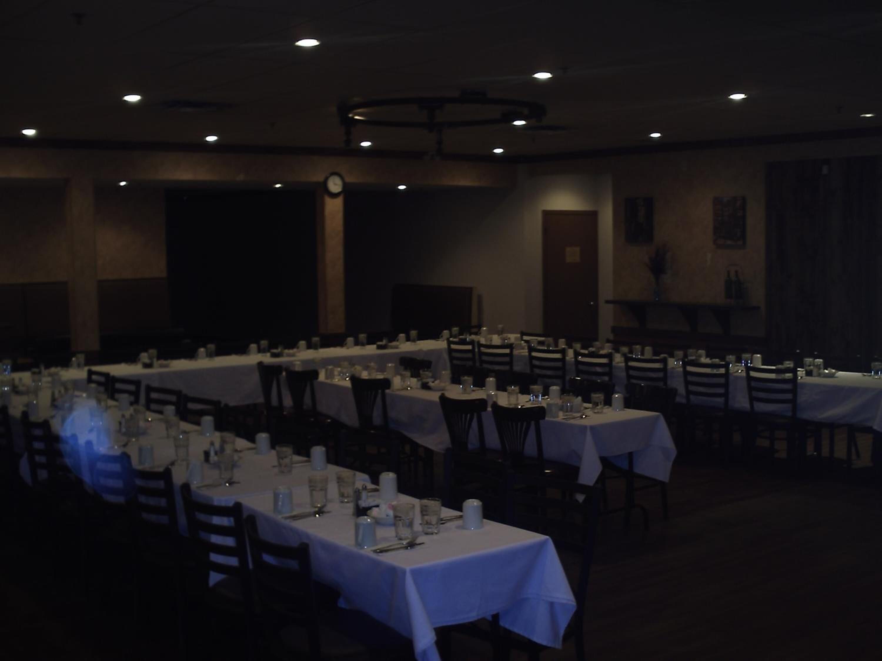 A banquet hall with multiple tables set for dining, equipped with chairs and table settings.