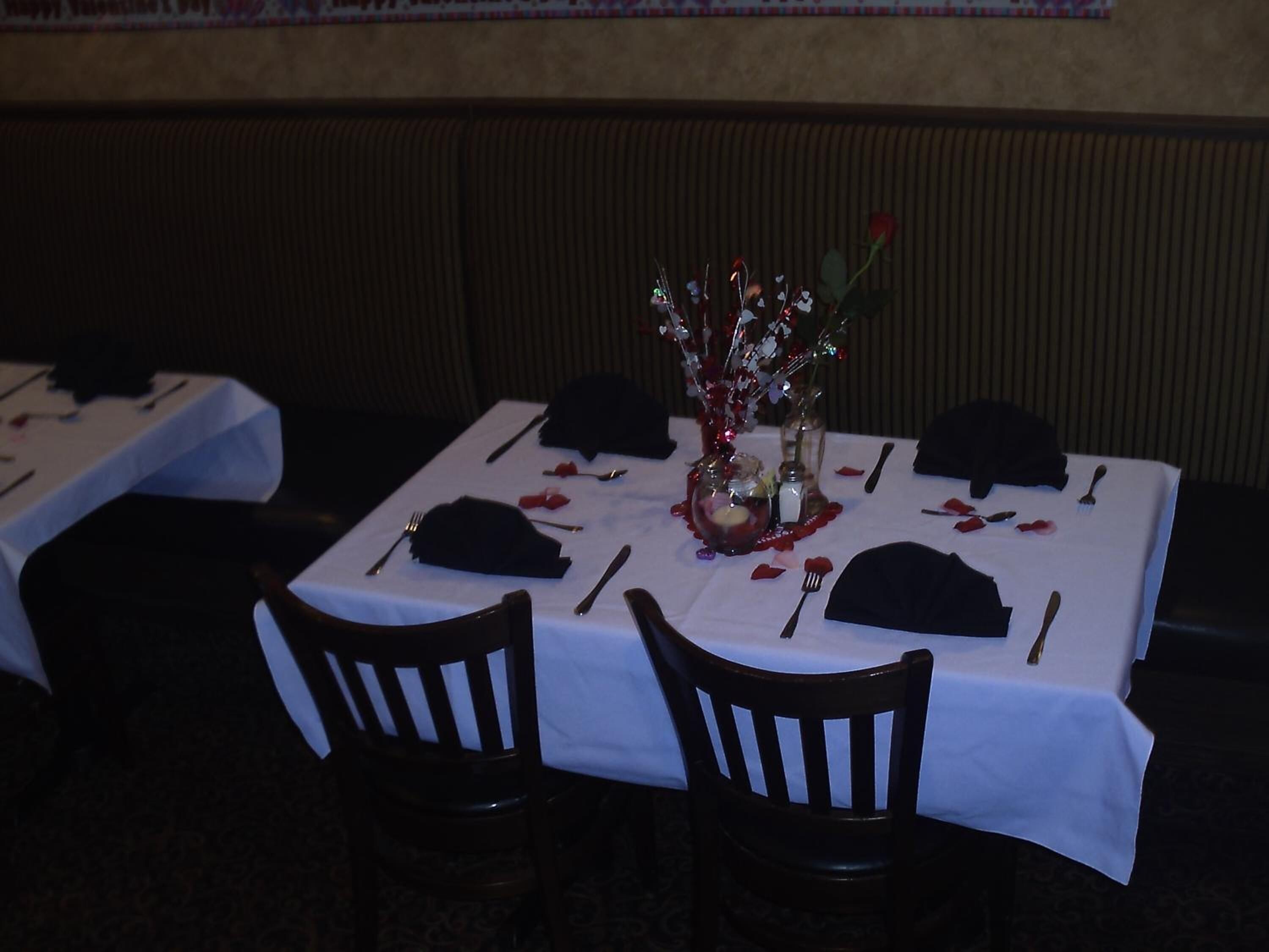 Una mesa de comedor dispuesta con un jarrón de flores, servilletas y cubiertos.