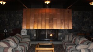 A cozy living room with striped sofas, a wooden coffee table, and a stone fireplace. - Burntwood Hotel (Thompson)